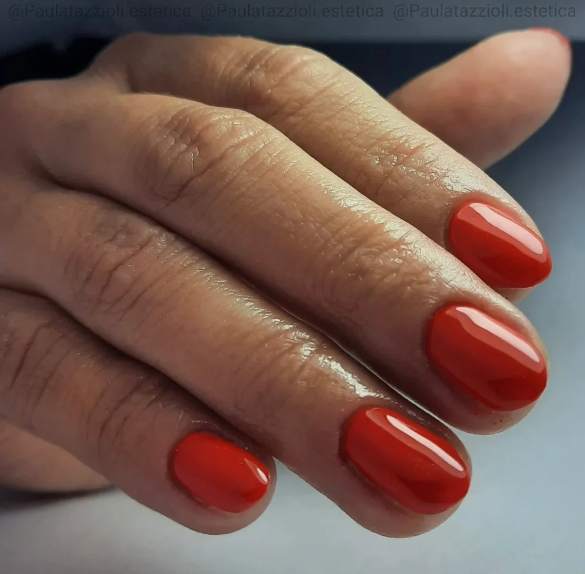 Capping premium en rojo coral sobre uñas redondeadas