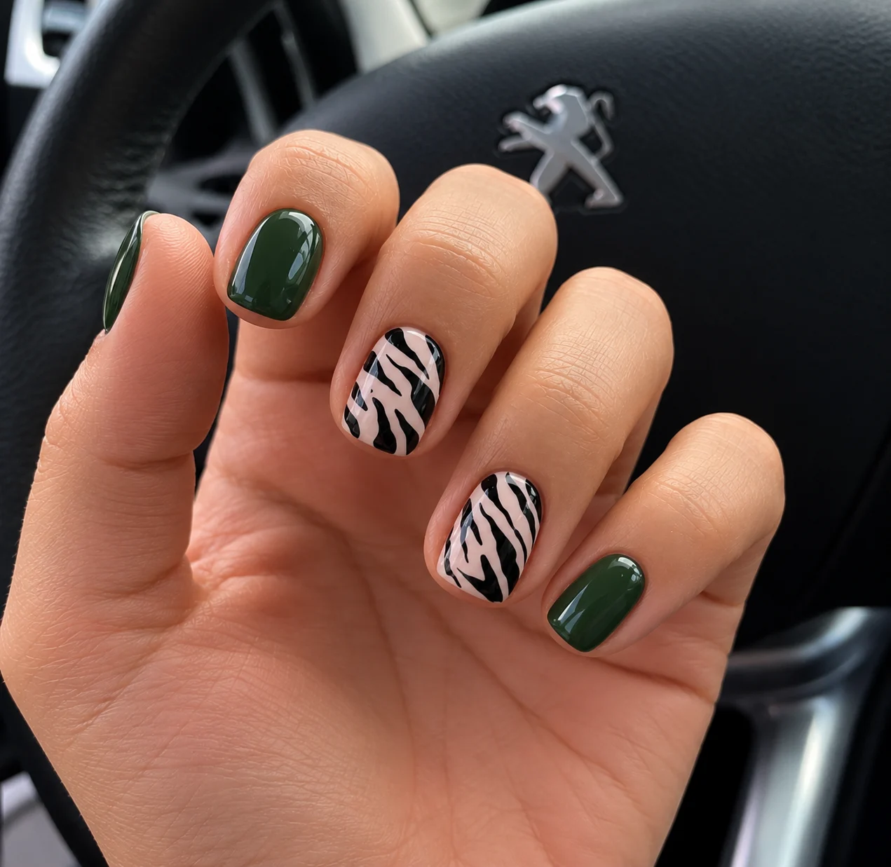 Esmaltado semipermanente verde oscuro con dos uñas de diseño animal print en blanco y negro